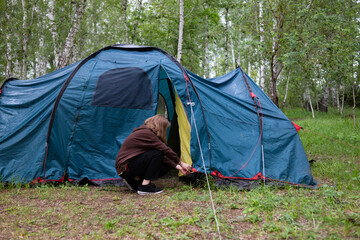 A woman sets up a tent in the forest. Journeys.