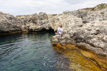 The girl at Cape Tarkhankut. The rocky coast of the Dzhangul Reserve in the Crimea. Turquoise sea...