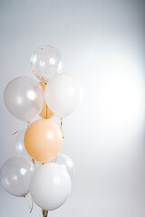 Balloons in white, beige and transparent colors on a gray background.