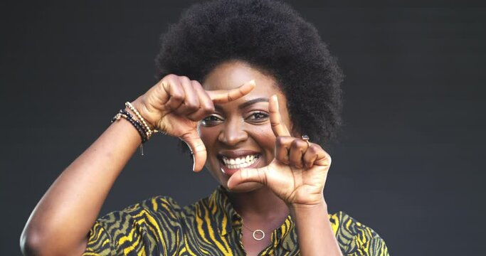 Face, happy and a woman with a hand frame, positive attitude and afro hair on a grey background. Portrait, black person and photography with confidence, smile and closeup for photographer creativity