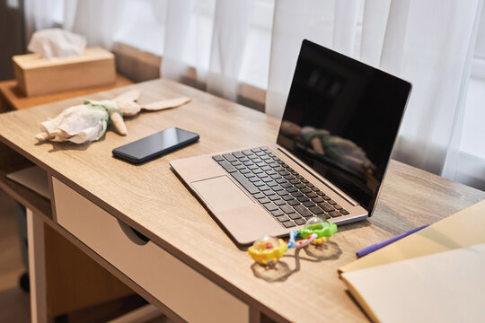 Background image of laptop on desk at home office with baby toys, working parent concept, copy space