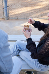 Couple eats yogurt and protein bar on bleachers outside