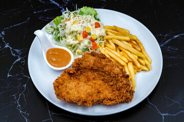 Steak fried pork with pepper sauce with french fries and vegetable salad put in dish on black marble background. Meat steak and french fries serving plate fast food meal. Delicious Steak meal set.