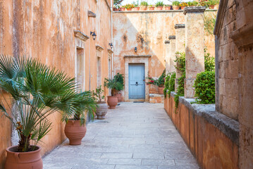 Exterior of an ancient building with fresh flowers in a clay pot on a sunny day, Crete, Grece