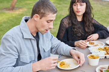 Couple eats Indian food at picnic table