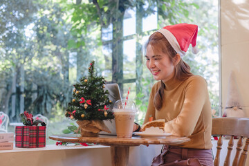 Obraz premium A startup employee writes a report on a laptop on Christmas Eve. In an office decorated with colorful bulbs and lights during the Christmas holidays