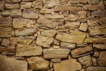 Close-up of Textured Stone Wall with Brickwork and Wood Detail. Textured stone wall with wood and brickwork patterns.