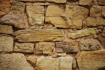 Close-up of Textured Stone Wall with Brickwork and Wood Detail. Textured stone wall with wood and brickwork patterns.