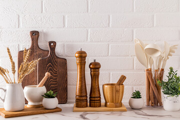 Various wooden kitchen utensils and cooking tools on the marble countertop. Front view. Stylish kitchen background.