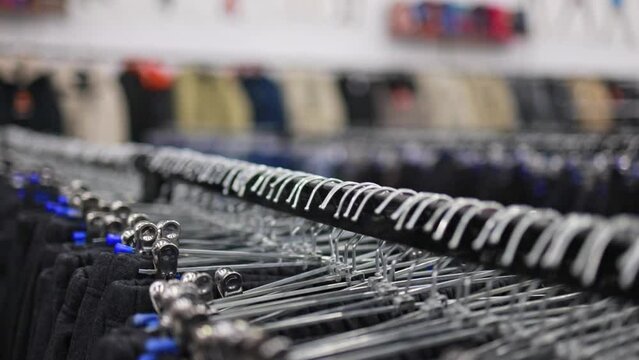 There are a lot of trousers on hangers in the store.