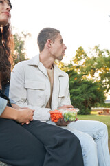 Couple snacks on vegetable platter in park