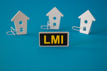 Wooden houses sits next to a wooden black board with the word LMI. Beautiful blue background, copy space Business and LMI concept.