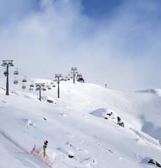 Fototapeta na wymiar Off-piste snowy ski slope and ski-lift at sunny winter evening