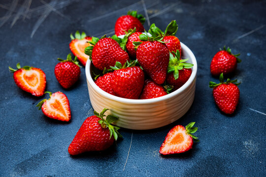 Fresh red strawberries, organic strawberries in white bowl on black background, close-up.