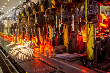 Glass factory, production of glass containers. Molten glass is blown into molds. Robotics in...