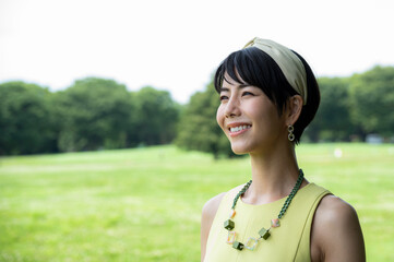 Portrait of a beautiful Asian woman happily smiling in a lush green park.