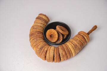 Figs or dried figs on white bowl with white background, Figs or dried figs arranged in round shaped on the white background in a wooden bowl. The fig is the edible fruit of Ficus Carica