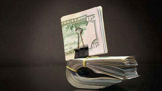 stack of dollar bills collected in an elastic band and a stationery clip