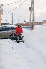 A man clear snow from backyard with snow blower. Winter season and snow blower equipment