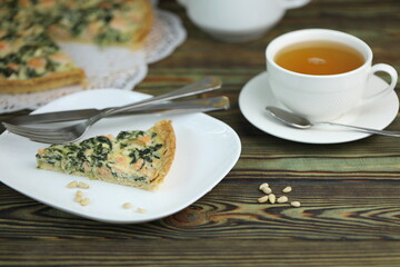 Delicious Quiche pie with salmon fish and pine nuts filling. Breakfast with quiche and cup of tea