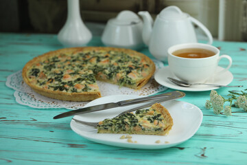 Delicious Quiche pie with salmon fish and pine nuts filling. Breakfast with quiche and cup of tea