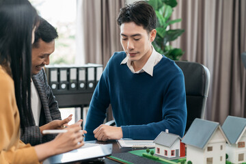 Real estate broker agent presenting and consult to customer to decision making sign insurance form agreement, home model, concerning mortgage loan offer in office.