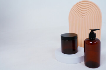 Composition with geometric shapes.body care. bottle with a dispenser and a jar of cream, on a light gray background. Advertising concept