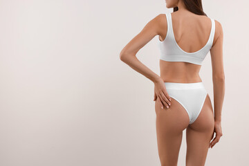 Fototapeta na wymiar Young woman in stylish bikini on white background, closeup. Space for text