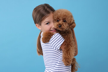 Little child with cute puppy on light blue background. Lovely pet