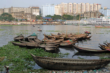 Fototapeta na wymiar People on both sides of the Buriganga river in Dhaka cross the river by traditional boat in this country because of the mother river.