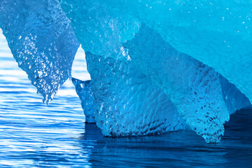 Detail of blue glacial ice at the base of an iceberg. This ice is from compressed snow, that has hardened over hundreds of years and broken from the glacier during a calving. In a fjord in Svalbard.