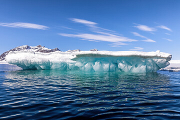Glacial blue iceberg and sky background. Underside of a snow covered iceberg in Svalbard, a...