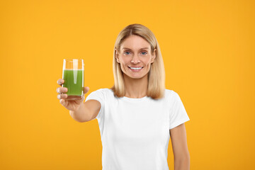 Happy woman with glass of fresh celery juice on orange background