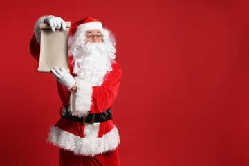 Merry Christmas. Santa Claus showing blank paper sheet on red background, space for text