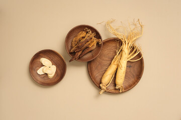 Fresh ginseng roots, ginseng slices and red ginseng on wooden dishes on beige background. Scene for medicine advertising, photography traditional medicine content © Tuan  Nguyen 