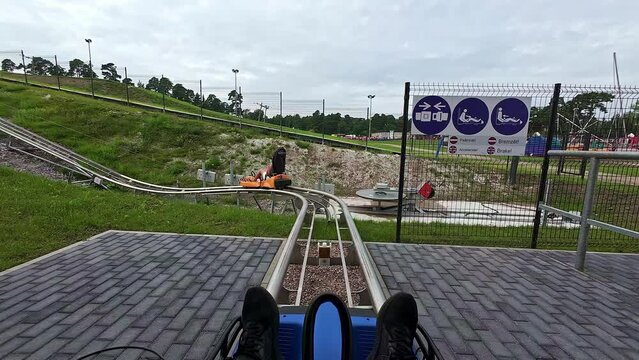 Person on small fun fair roller coaster ride watches as person ahead starts moving. Slow Motion
