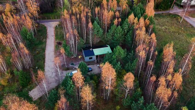 drone flying away from a charming wooden hut on a vibrant autumn day