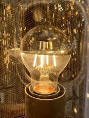 Luminous Reflections.A glowing bulb's filaments set against a backdrop of crisp, geometric reflections, offering a juxtaposition of warmth and precision.