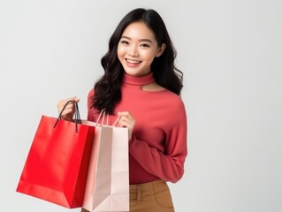 Fototapeta na wymiar happy Asian woman holding paper shopping bags on pastel colored background