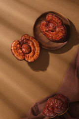 Scene of rare raw materials used for cosmetics - lingzhi mushrooms on wooden dish with brown cloth...