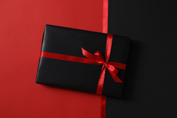 Ribbons and gift box on red background, top view