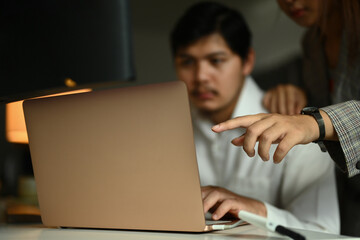 Creative designer team looking at laptop screen while working on design project together