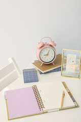 Notepads, pen and alarm clock on white background, space for text