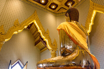 Golden statue of Buddha with a saffron robe inside the ornate Wat Songkhram, Bangkok, Thailand