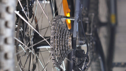 Close-up of mountain bike drivetrain. Cassette with chain. On the other side of the wheel brake disc with caliper. Bicycle repair and maintenance in a specialised workshop.