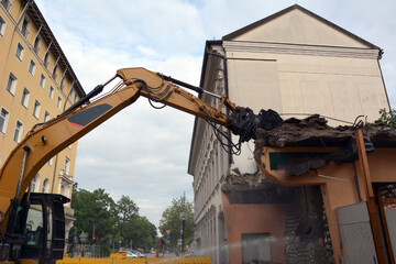 Dismantling by builders of an old building with several floors using an excavator with a...