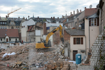 Construction site with demolition work by builders of an old building using an excavator with a...
