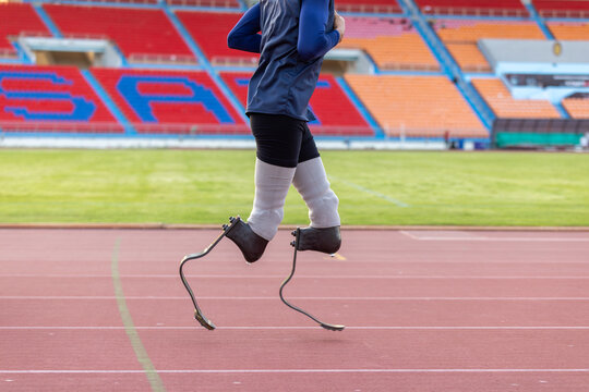 Asian para-athlete with prosthetic blades leg in stadium practicing workout for Paralympic running competition. Amputee sportsman runner practicing running workout. Disabled athlete man sport concept.