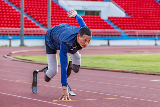 Asian para-athlete with prosthetic blades leg in stadium practicing workout for Paralympic running competition. Amputee sportsman runner practicing running workout. Disabled athlete man sport concept.