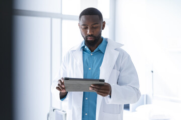 African american male doctor using tablet in hospital room - obrazy, fototapety, plakaty